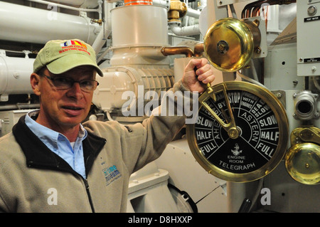 Bob Desh, geschäftsführender Direktor des Schifffahrtsmuseums Door County, posiert mit einem Motor Raum Telegraph in der Schlepper John Purves Stockfoto