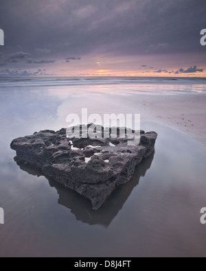 Ein riesiger Felsen steht in ein Pook des Wassers im Dunraven Bay an der Küste von Glamorgan Heritage in Wales als die Sonne untergeht dahinter. Stockfoto