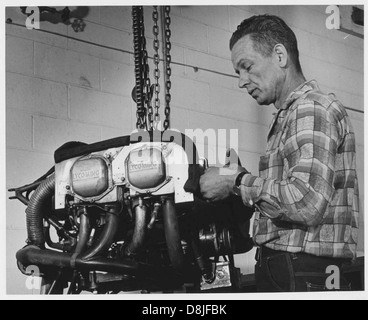 Ein Vintage-Foto eines Mannes, der an einem Flugzeugmotor arbeitet, zeigt die komplizierten mechanischen Arbeiten. Dieses Bild veranschaulicht die frühe Luftfahrttechnik und die handwerkliche Arbeit bei der Wartung von Flugzeugen während der frühen Luftfahrt. Stockfoto
