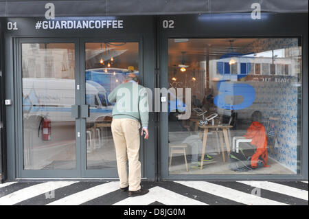 Shoreditch, London, Uk. 30. Mai 2013. Ein Mann schaut durch das Fenster des #Guardiancoffee Shops in Shoreditch. #Guardiancoffee einem temporären Popup-Café in Shoreditch öffnet für drei Monate mit iPads auf den Tischen und einem interaktiven Bildschirm zeigt Tweets und Kaffee-Verkauf. Bildnachweis: Matthew Chattle/Alamy Live-Nachrichten Stockfoto