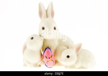 Keramik-Hase-Trio mit ein Easter Egg auf dem weißen Hintergrund isoliert. Stockfoto