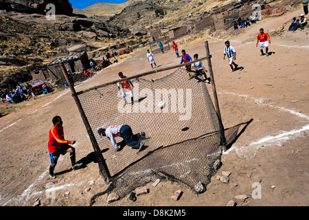 Einheimische Männer spielen Fußball auf einem Fußballplatz Schmutz in die ländliche Berggemeinde in der Nähe von Puno, Peru. Stockfoto