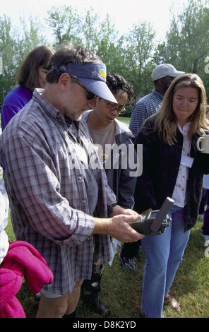 Eine Gruppe von Menschen, die sich im Freien versammelten und möglicherweise eine Freizeitbeschäftigung oder eine soziale Aktivität ausüben. Das Bild zeigt die Vielfalt und Aktivität der Gruppe in einer offenen Umgebung im Freien, mit Natur- oder urbanen Elementen im Hintergrund. Stockfoto