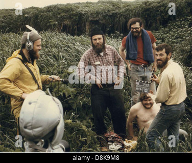Ein TV-Team, das sich darauf vorbereitet, Arbeiter im Außendienst zu befragen. Die Szene zeigt die Arbeiter und die Crew, die das bevorstehende Interview mit Kamera und Beleuchtungsausrüstung diskutieren. Stockfoto