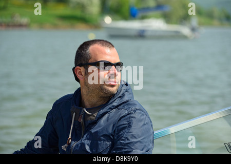 Mann sitzt in einem Motorboot mit einem anderen außerhalb des Fokus in einer Bucht Stockfoto