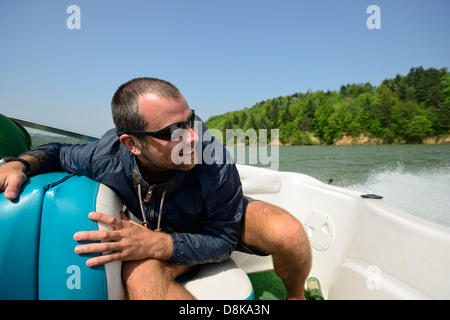 Mann in einem Motorboot Beschleunigung Weg entlang der Küste, hält dicht und lächelnd Stockfoto