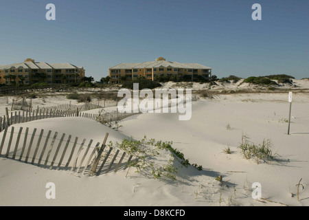 Ein verwitterter Holzzaun säumt den Rand eines Sanddünen-Bereichs und schützt die Umgebung vor Erosion. Die natürliche Umgebung bietet weichen Sand und Küstengräser. Stockfoto