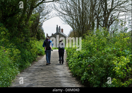 Eine junge Familie zu Fuß auf einer Straße in Penberth Cove in Cornwall. Stockfoto