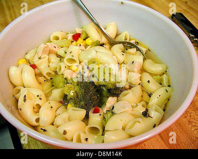 Eine Schüssel mit dampfender Hühnernudelsuppe mit zarten Hühnerstückchen, Nudeln und Gemüse in einer aromatischen Brühe, die eine angenehme und nahrhafte Mahlzeit bietet. Stockfoto