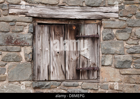 alte Holztür in Steinwand, verwittert, unlackiert, hölzerne Lintol, Scharniere rostiges Eisen Stockfoto