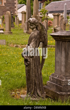 Weibliche Engelsstatue neben einem großen Grabstein innerhalb der Erde eines Friedhofs in Broughty Ferry in der Nähe von Dundee, UK Stockfoto