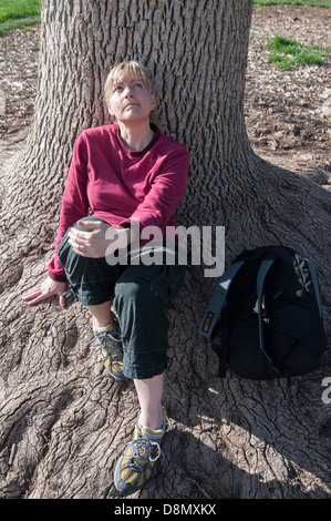 Frau sitzt unter einem Baum in Gedanken. Stockfoto