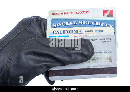 Ausweisdokumente (Sozialversicherung, Führerschein und Kreditkarte) in der Hand des Diebes, isoliert auf weiss. Stockfoto