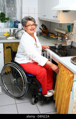 Frau in einem Rollstuhl in der Küche Stockfoto