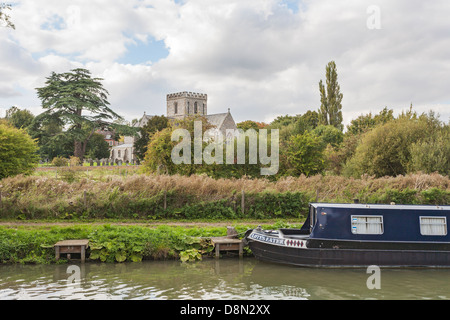 Großes Bedwyn, Wiltshire, England - Fluss Dun mit schmalen Boot und Str. Marys Kirche und Zeder im Hintergrund Stockfoto