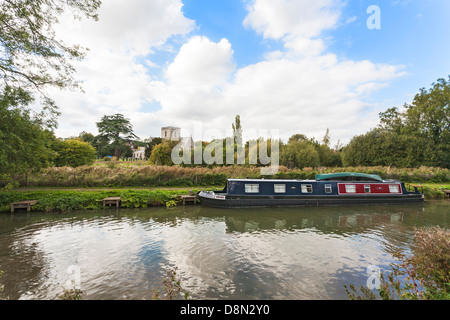 Großes Bedwyn, Wiltshire, England - Fluss Dun mit Narrowboat und Str. Marys Kirche und Zeder im Hintergrund Stockfoto