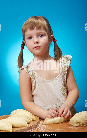 Lächelnd wenig Mädchen kneten Teig in Küche mit eine Torte backen Stockfoto