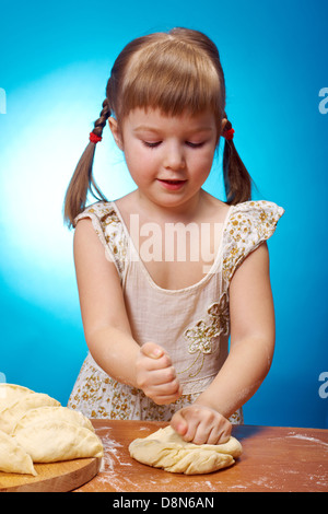 Lächelnd wenig Mädchen kneten Teig in Küche mit eine Torte backen Stockfoto