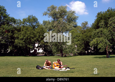 Junge Frauen, die das Gitarrenspiel in einem Park in der Kampa Insel wenig Viertel Prag Tschechische Republik Stockfoto