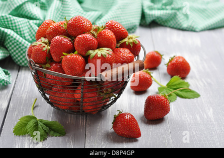 Frische rote Erdbeeren in einen Metallkorb auf hölzernen Hintergrund Stockfoto