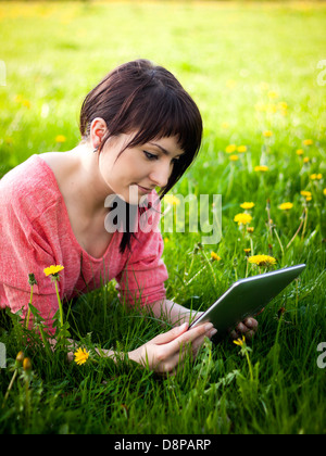 Junge Frau mit Tablet im Freien auf dem Rasen verlegen Stockfoto