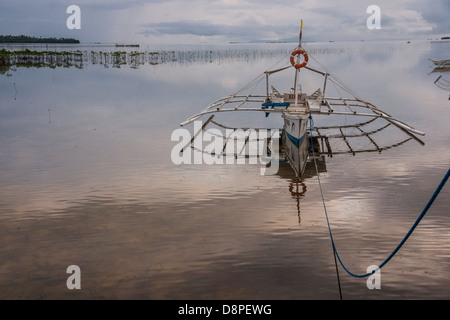 Ausleger Bangka - einem traditionellen philippinischen Fischerboot - namens Henry gebunden zum pier Stockfoto