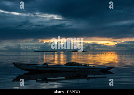 Klein vertäut Ausleger Bangka - einem traditionellen philippinischen Fischerboot - in den Sonnenuntergang Stockfoto
