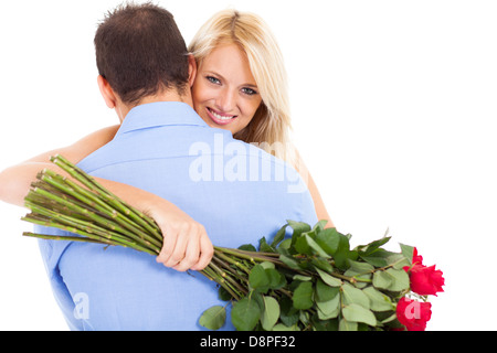 junge Frau umarmt Freund mit Rosenstrauß Stockfoto