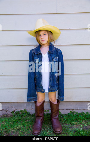 Kleines Kind Mädchen vorgibt, ein Cowboy mit Vater Stiefel und Hut Stockfoto