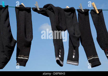 Socken und Hose gekoppelt an eine Wäscheleine vor dem Himmelshintergrund Stockfoto