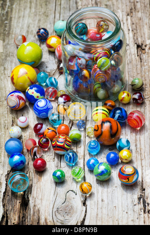 Bunte Murmeln und Glas jar auf altem Holz Stockfoto