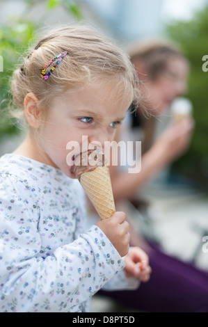Niedliche kleine Mädchen mit blonden Haaren ist Eis essen. Stockfoto