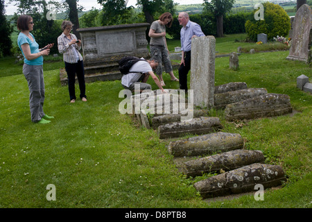 Besucher inspizieren die Reihe der Childrens Gräber auf dem Friedhof der St. James, Kühlung, Kent. Charles Dickens schrieb über diese Gräber in der Öffnung seines berühmten Romans Great Expectations. Dickens wohnte in der Nähe in Higham und bezeichnet diese Reihe von Kinder Grabsteinen jetzt unweigerlich genannt Pip es Gräber. (mehr in Beschreibung...) Stockfoto