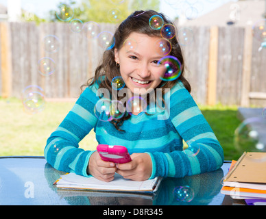 US-amerikanischer Latin Teen Mädchen mit Smartphone Hausaufgaben auf Hinterhof Stockfoto