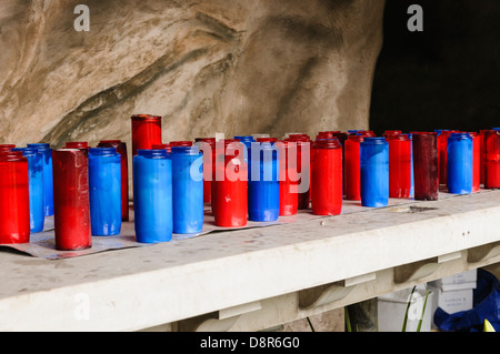 Blaue und rote Kerzen auf einem katholischen Kirche Altar Glas Stockfoto