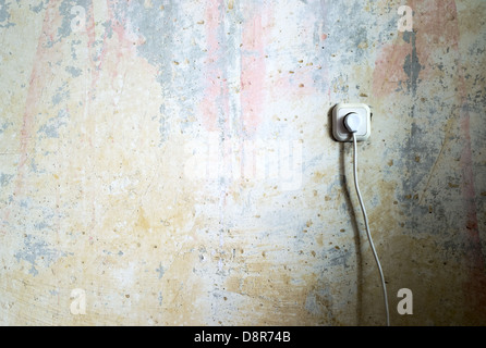 Steckdose und Kabel auf Grunge-Wand Stockfoto