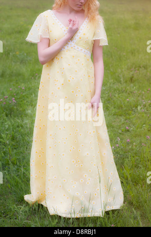 eine blonde Frau in einem gelben Kleid auf einer Wiese Stockfoto