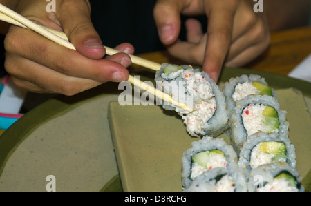 Nahaufnahme der Frau mit Stäbchen Sushi Roll abholen. Stockfoto