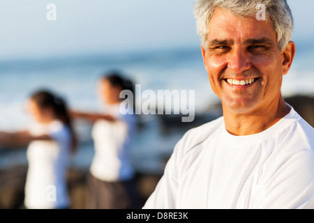 Lächeln auf den Lippen schöner aktiver senior Mann posiert am Strand mit Familie Stockfoto