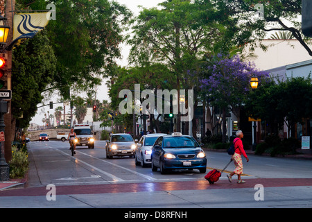 State Street in Santa Barbara, Kalifornien, die Autos mit Scheinwerfern auf Radfahrer und Fußgänger in der Abenddämmerung aufgenommen. Stockfoto
