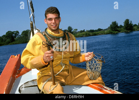 Ein Junge Schwamm Taucher Verschleißteil des Tauchanzuges eine traditionelle Glocke ruht auf einem Schwamm-Boot in den Golf von Mexiko in der Nähe von Tarpon Springs, Florida, USA. Stockfoto