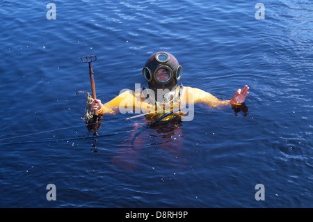 Ein Junge Schwamm Taucher in einer traditionellen Akkubohrschrauber Glocke Taucheranzug steigt mit seinem abwaschenden Rechen aus dem Golf von Mexiko in der Nähe von Tarpon Springs, Florida, USA Stockfoto