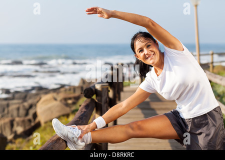 passen Sie Reife Frau Morgen stretching am Strand am Morgen Stockfoto