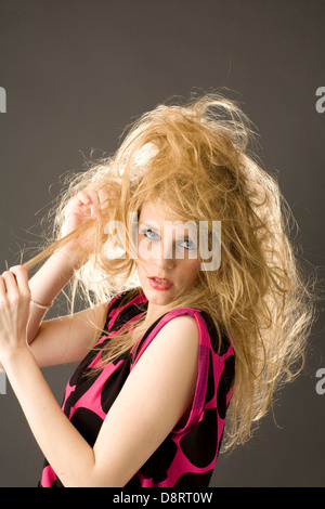 Blondine mit langen zerzaustes Haar Seite auf Kamera tragen rosa ärmelloses Top mit großen schwarzen Flecken Stockfoto