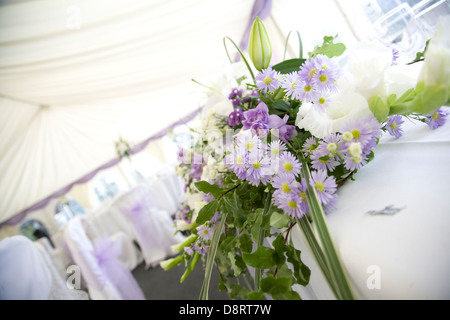 Blumenschmuck in lila, Flieder, weiß und grün mit Blick auf dekorierten Hochzeit Festzelt im Hintergrund Stockfoto