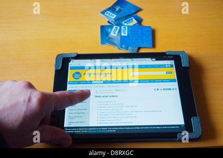 Person, die in UK Debt Relief Informationen über Internet auf dem Ipad Mini Tablet PC zu Hause Stockfoto