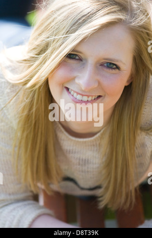 Hübsche blonde Frau im liegen auf einer Parkbank an einem Sommertag. Stockfoto