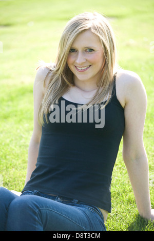 Hübsche blonde Frau sitzt in einem Park an einem Sommertag. Stockfoto
