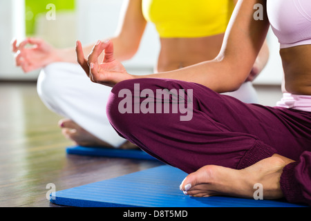 Junge Frauen, die Yoga und Meditation im Fitness-Studio für bessere Fitness, kaukasischen und latina Stockfoto