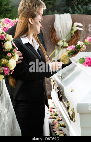 Trauer um Mann und Frau auf der Trauerfeier am Sarg oder Sarg mit rosa rose Stockfoto